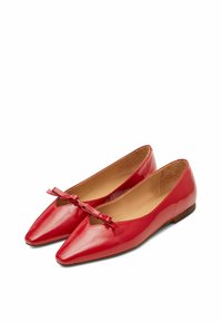 Ballerine in pelle rossa con punta affusolata e un dettaglio a fiocco sulla tomaia. Texture liscia con tacco basso e piatto. Interno beige.