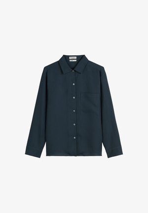 Chemise bleu marine à manches longues, avec col, poche avant unique et texture tissée. Présente des boutons métalliques sur le devant.