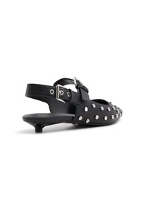 Chaussure slingback en cuir noir avec des clous en argent, bout pointu et petit talon. Présente une sangle à boucle pour un ajustement sécurisé.
