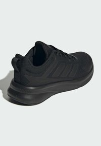 Chaussure de sport noire fabriquée avec une tige en maille respirante, dotée d'accents texturés, d'une semelle rembourrée et d'un onglet de talon renforcé pour un soutien.