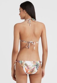 Bikini set s krkom a sťahovacími bokmi, s bielym pozadím a farebnými tropickými listovými vzormi. Hladká textúra látky.