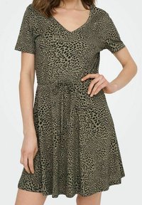 Kurzärmliges, V-Ausschnitt-Kleid in Olivgrün mit gepunktetem schwarzen Leopardenmuster. Mit verstellbarem Kordelzug in der Taille und einem schwingenden Rock. Glatte Textur.