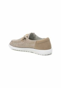 Zapato textil marrón con parte superior de malla, parte trasera suave similar a ante, puntera redonda y suela de goma blanca. Presenta cordones y ojales decorativos.