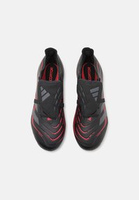 Black and red soccer shoes with a streamlined design, textured upper, flexible fit, and a cover over the laces for increased control.