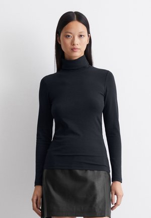 Tricou negru cu guler înalt, cu mânecă lungă, într-un design ajustat, realizat dintr-un material moale și elastic. Purtați cu o fustă din piele neagră.