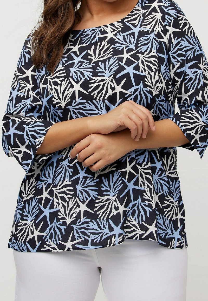 Haut noir avec un motif corail en bleu clair et blanc, doté de manches trois-quarts et d'un col arrondi.