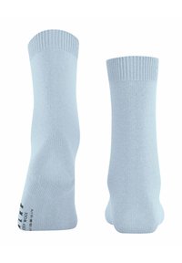 Due calzini di lana blu chiaro in piedi, uno che mostra il lato interno con del testo, l'altro che mostra il lato esterno.