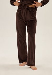Brązowe welurowe spodnie dresowe o luźnym kroju, z elastycznym pasem na sznurek i miękką teksturą, idealne na co dzień.
