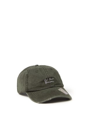 Dark green baseball cap with "Not Your Business" embroidered in white on front, and a small sticker on the curved brim.