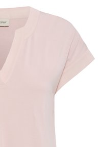 Haut rose clair à manches courtes avec un col en V et une texture de tissu douce et lisse.