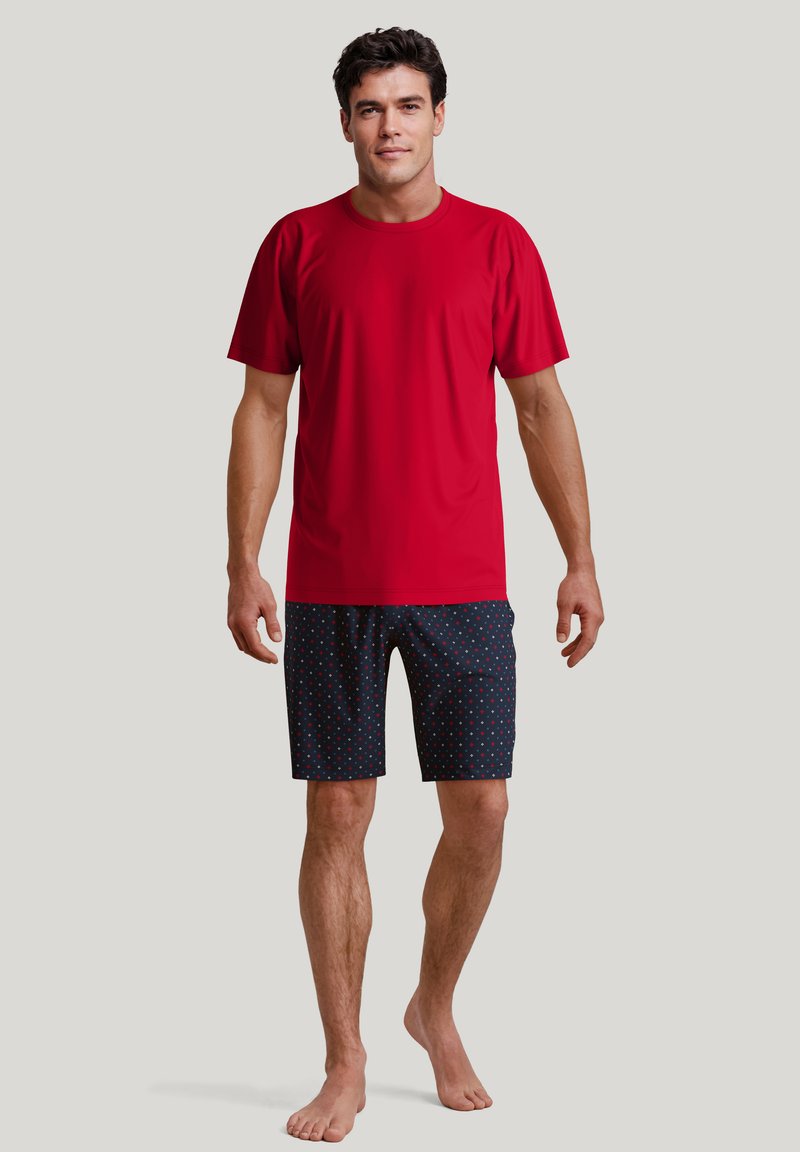 Rode t-shirt met korte mouwen gecombineerd met marineblauwe gestreepte korte broek met kleine meerkleurige stippen. Het ontwerp is casual en comfortabel.