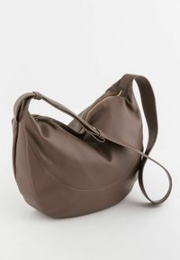 Bolso de hombro de cuero marrón con diseño curvo, que cuenta con una sola correa y una cremallera dorada. Superficie texturizada con bordes suaves y redondeados.