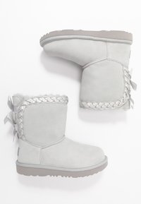 Szare zamszowe botki za kostkę z plecionym srebrnym akcentem, okrągłym noskiem i dopasowanym detalem wstążki po boku. Miękka podszewka i fakturowana podeszwa.