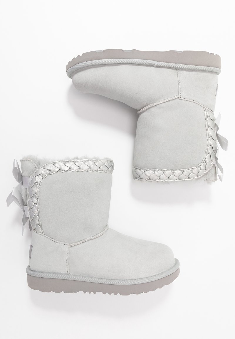 Szare zamszowe botki za kostkę z plecionym srebrnym akcentem, okrągłym noskiem i dopasowanym detalem wstążki po boku. Miękka podszewka i fakturowana podeszwa.