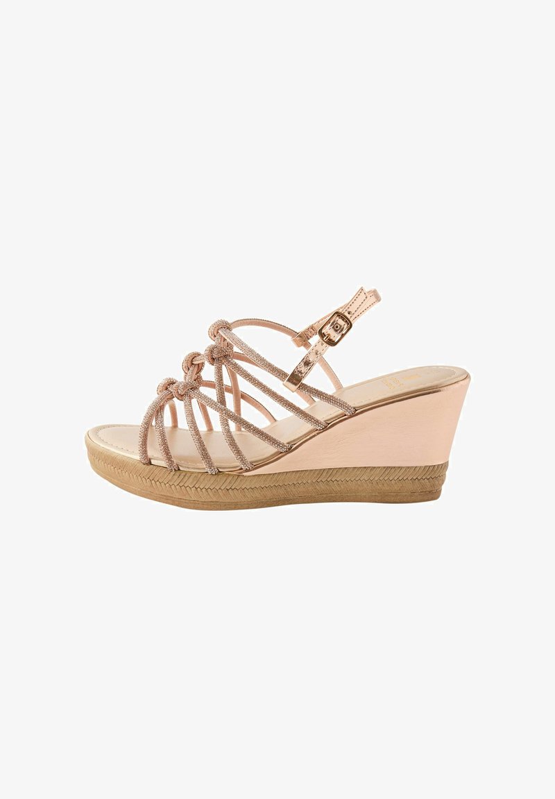 Wedge sandal with a shiny rose gold upper, featuring multiple crisscrossed straps and a buckled ankle strap; textured platform sole.