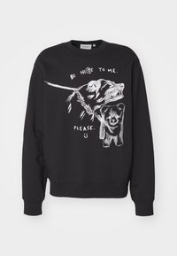 Sudadera negra con un gráfico de la cara de un oso y un osito de caricatura, con el texto "SÉ BUENO CONMIGO. POR FAVOR." en blanco.
