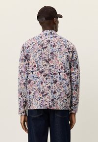 Ζακέτα με λουλουδάτο μοτίβο σε ανοιχτό μπλε, με συνδυασμό από ροζ, μοβ και σκούρα κόκκινα λουλούδια· μακριά μανίκια και κλασικός σχεδιασμός για το γιακά.