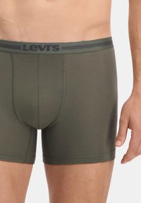 Olívazöld boxeralsó, puha, sima textúrával. Fekete Levi's logó található derékrészen. Közepes hosszúságú szabás, varrott varratokkal.