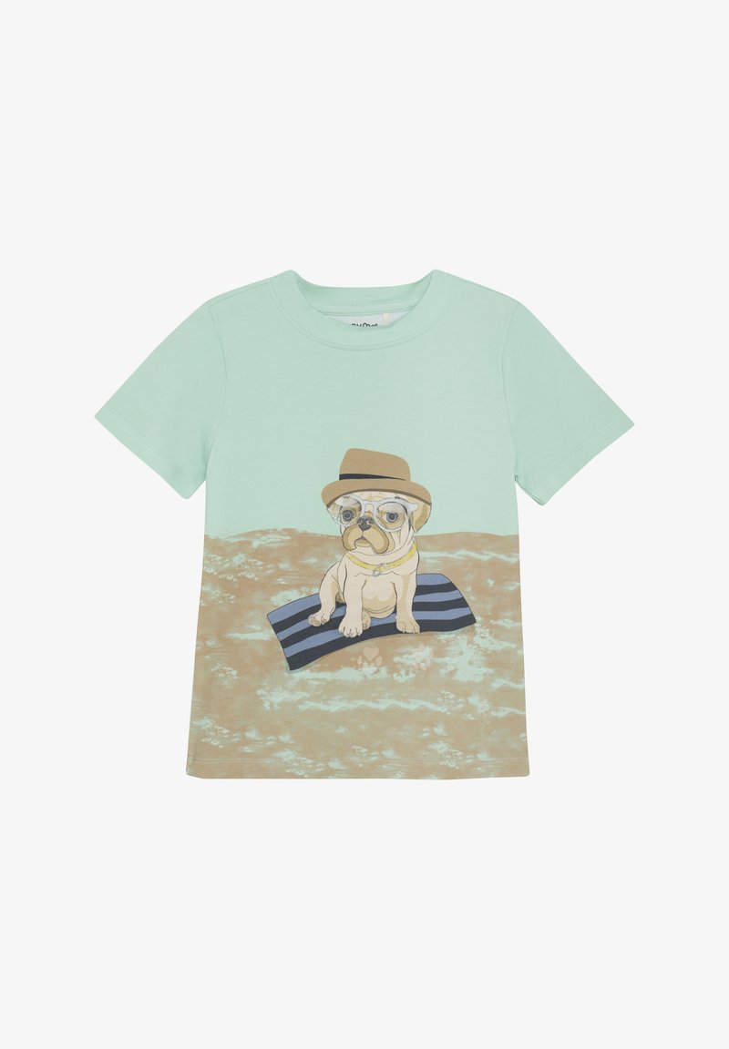 Mintgrøn t-shirt med et grafisk design af en mops, der bærer briller og en hat, siddende på et stribet tæppe mod en sandet baggrund.