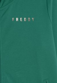 Felpa verde con una texture liscia, cappuccio e scritta in lettering metallico argento che spellano "FREDDY" sul petto.