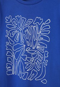 Art floral abstrait blanc en ligne avec diverses formes de feuilles et de fleurs sur un fond de tissu bleu.