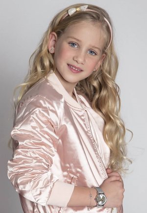 Rosa Satin Bomberjacke mit geripptem Saum, langen Ärmeln und Reißverschluss. Eine silberne Uhr mit Milanaiseband und einem hellen Haarband mit Schleifen.