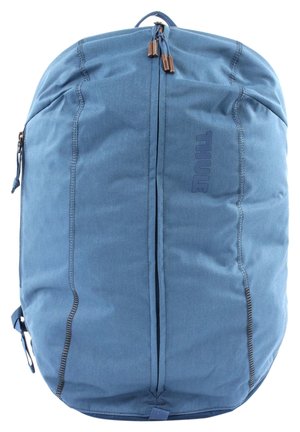 Blaue Stoff-Rucksack mit rundem Design. Glatte Textur, doppelte Reißverschlüsse und ein prominent auf der Vorderseite angebrachtes Logo.