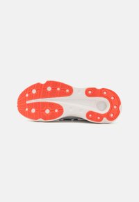Sports shoe sole with a textured white base and bright orange rubber patterns for traction, featuring circular and linear grooves.