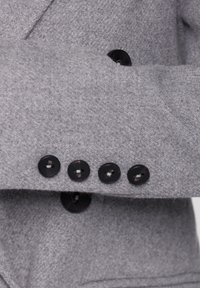 Gr�å uldblazerærme med fem sorte knapper, glat tekstur med let glans, skræddersyet pasform med struktureret skulderdesign.