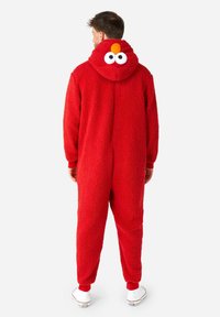Mono de felpa rojo con capucha que presenta un diseño de personaje, ojos grandes y un pico naranja. Los puños y los tobillos tienen bandas elásticas rojas.