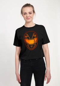 Sort bomuld t-shirt med et orange grafisk design af en stiliseret maske med skarpe træk og geometriske detaljer på forsiden.