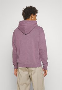 Sudadera con capucha en lavanda apagada, hecha de forro polar texturizado. Cuenta con una gran capucha, puños acanalados y un corte holgado.