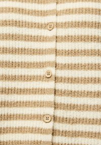 Béžová a bílá pruhovaná pletená látka s třemi světle hnědými čtyřdírkovými knoflíky v svislém řádku uprostřed.