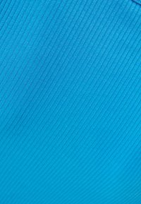 Gros plan sur un tissu bleu avec une texture à fines nervures diagonales et des variations subtiles de couleur.