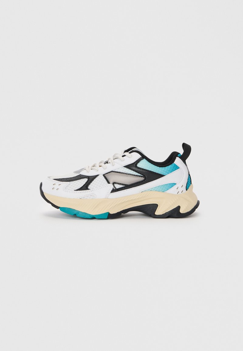 Zapatilla deportiva blanca con detalles en negro y verde aguamarina, parte superior texturizada, diseño con cordones, suela gruesa y estrías distintivas en la suela exterior.