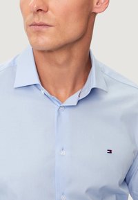 Camicia azzurro chiaro in tessuto liscio, con colletto classico, taglio slim e un piccolo logo ricamato sul petto.