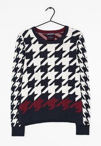 Il maglione presenta un motivo a scacchi in bianco, nero e bordeaux. Realizzato in tessuto lavorato a maglia, ha un collo rotondo e maniche lunghe.
