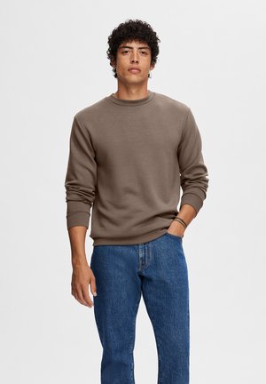 Bruine sweatshirt met een ronde halslijn en geribbelde mouwen. Gecombineerd met blauwe spijkerbroeken. Soepele textuur, relaxte pasvorm. Eenvoudig ontwerp.