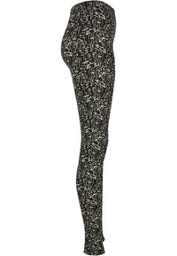 Leggings neri con un motivo astratto bianco. Tessuto elastico con un design aderente, svasato alla caviglia.