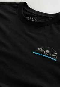 Sort bomulds t-shirt med en hvid kontur af Vitruvian Mand grafikken og teksten "L'uomo Vitruviano" i blå. Crew neck design.