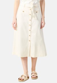 Beige puolipitkä hame, joka on valmistettu puuvillasta, sisältää solmittavan vyön, etupainikkeet ja kaksi taskua vyötäröllä. Suuri tekstuuri ja rento muotoilu.