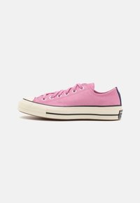 Rosa canvas låg-top sneakers med rund tå, vit gummisula, kontrasterande svart rand och metallöglor för snören.