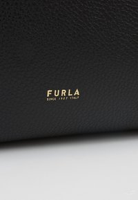 Czarna skórzana powierzchnia ma teksturowany wzór. Nazwa marki "FURLA" oraz "SINCE 1927 ITALY" są wytłoczone w złocie.