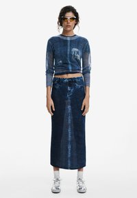 Denim crop sweater with long sleeves, paired with a high-waisted denim maxi skirt. Both in dark blue featuring faded patterns.