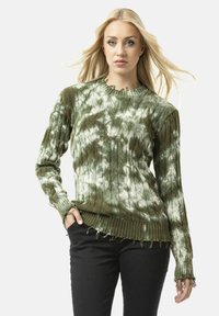 Olivgrüner Zopfmuster-Pullover mit Fransen am Saum und rüschigem Ausschnitt. Verfügt über strukturierte Fasern und eine figurbetonte Passform.
