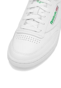 Tenisi din piele albă, cu zonă perforată la vârful pantofului, șireturi plate, logo Reebok verde și talpă din cauciuc texturat.