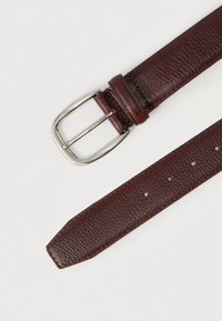 Pruun nahast vöö tekstureeritud pinnaga, hõbedane ristkülikukujuline pandlaga ja mitu reguleerimiseks mõeldud auku; otsad on veidi kitsenevad.