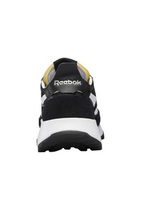 Baskets Reebok noir et blanc vues de dos, montrant le nom de la marque sur la languette du talon et une semelle intermédiaire blanche avec une semelle extérieure noire.