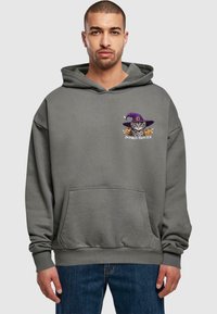 Grå huvtröja med en framficka, med en grafik av en katt i en lila häxhatt och pumpor, märkt "PUMPKIN PROWLER."