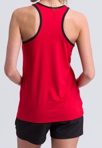 Top deportivo rojo sin mangas con diseño de espalda nadadora, con un contraste negro en los bordes y textura suave; acompañado de pantalones cortos negros.